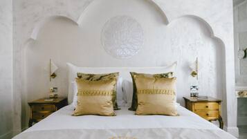 A bed with a white headboard, two decorative pillows, and a geometric wall design.
