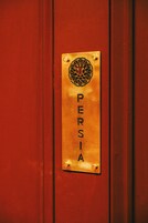 A red door with a brass plaque that reads "PERSIA."