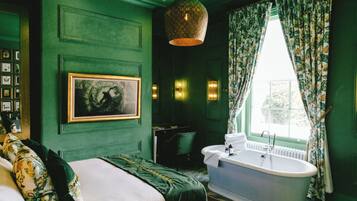 A room with a bed, a bathtub, and a window with curtains.