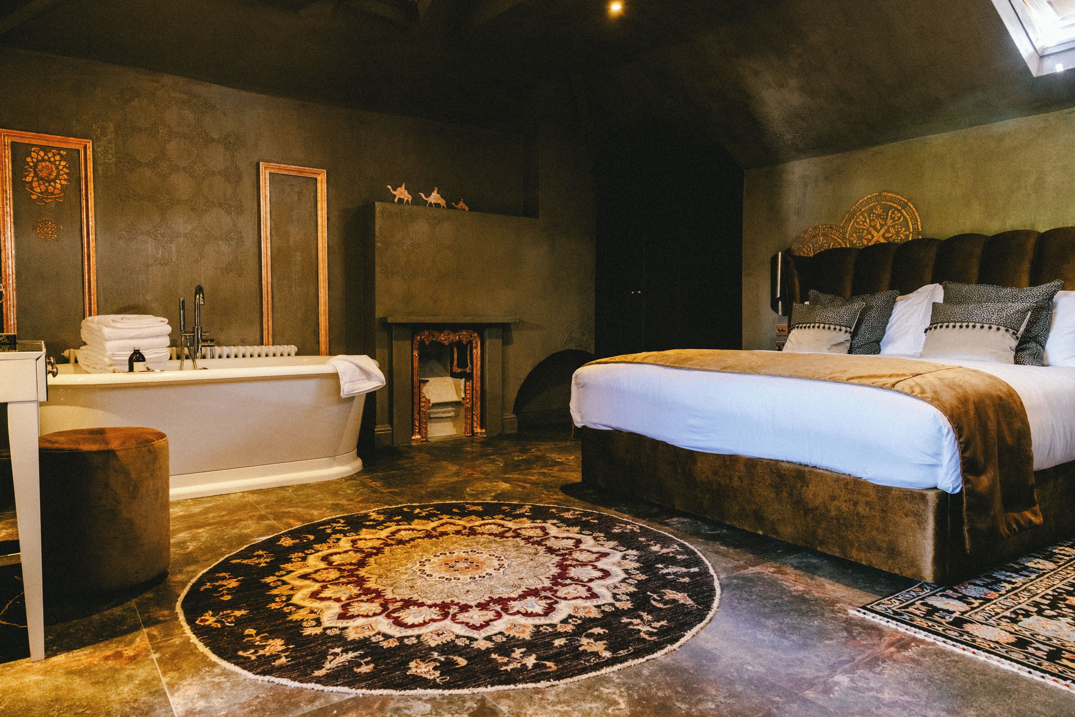 A bedroom with a large bed, a bathtub, and a fireplace.