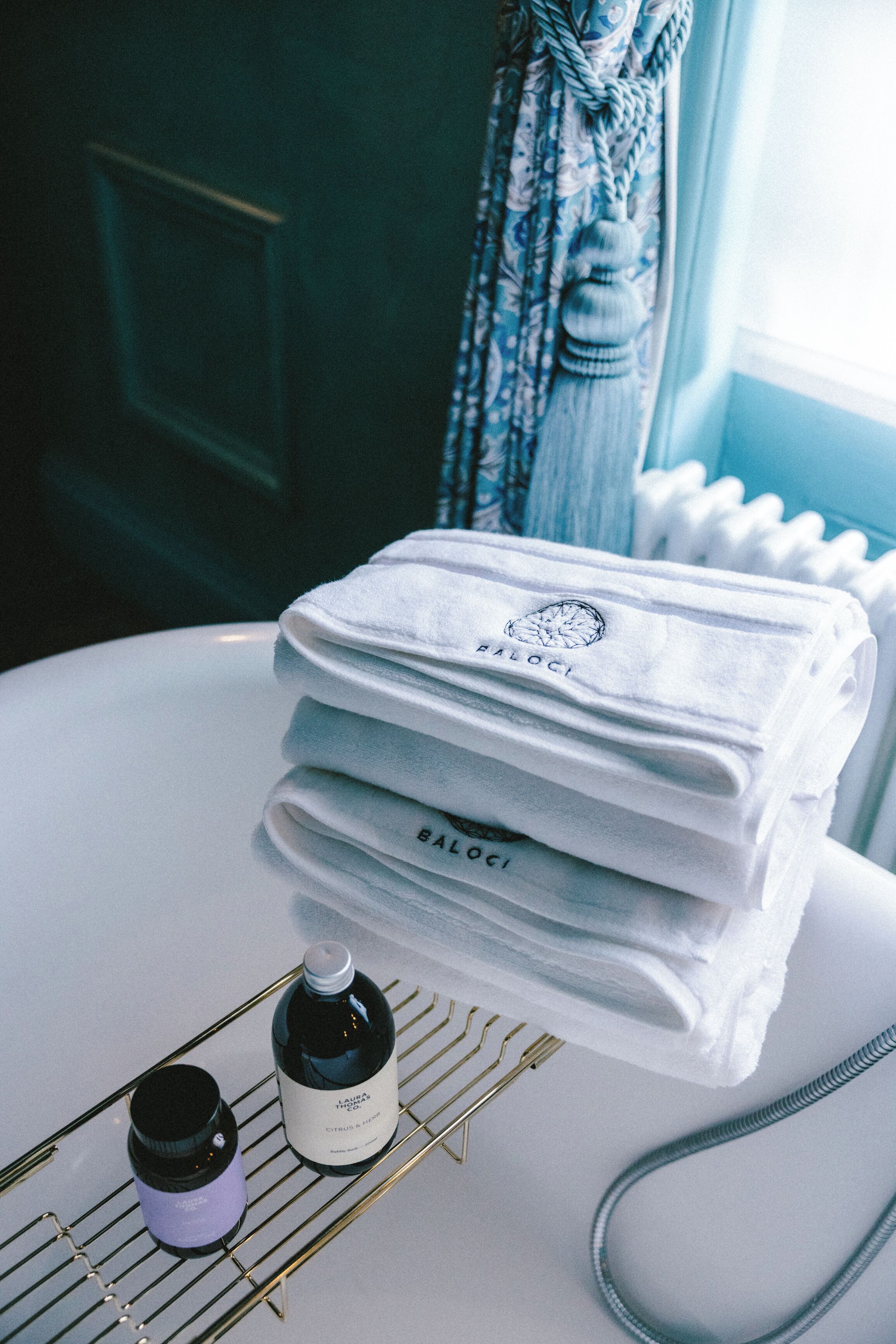 A neatly arranged bathroom with a stack of white towels, a bottle of lotion, and a hairdryer on a white surface.