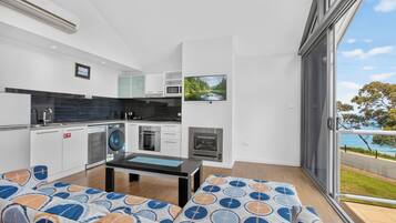 Una cocina moderna con electrodomésticos integrados, un comedor con mesa y sofá estampado, y un amplio ventanal corredero a un espacio exterior con vistas panorámicas.