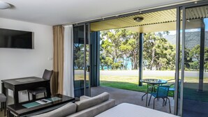 A hotel room with a bed, a desk, a TV, and a balcony with a table and chairs. - Lufra Beachside Hotel (Eaglehawk Neck)