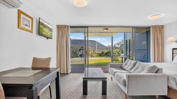 Habitación de hotel con cama, sofá, escritorio y vistas a un paisaje montañoso.