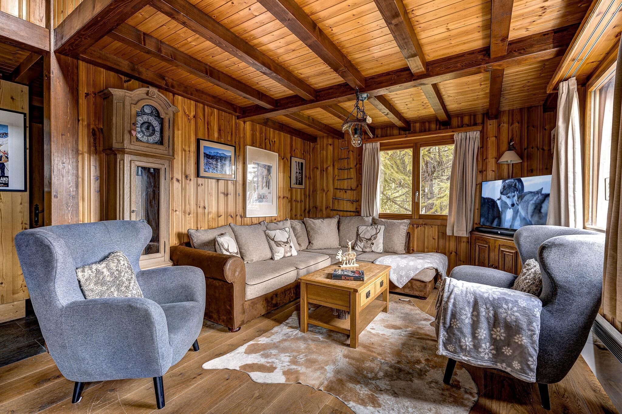 L’intérieur chaleureux d’un chalet avec des murs en bois, un ensemble de canapés, une table basse et un téléviseur.