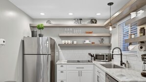 Una cucina moderna con frigorifero in acciaio inox, mobili bianchi, forno a microonde integrato e lavello.