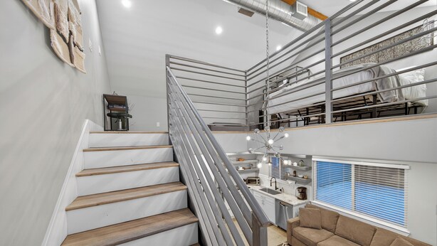 Un interno moderno con una scala, un divano e una zona cucina.