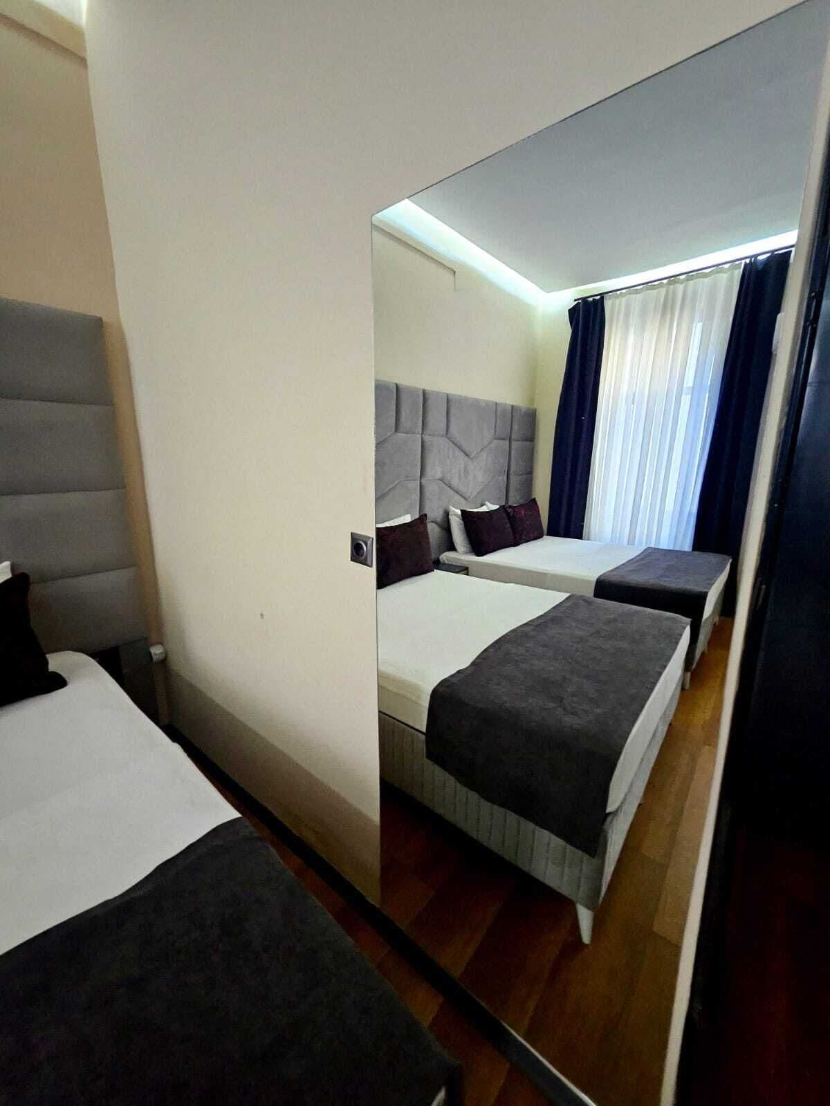 A hotel room with two beds, a large mirror, and a view of the room through the mirror.