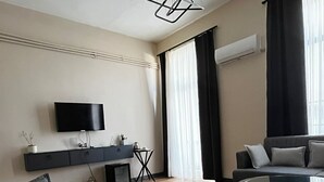 Een moderne woonkamer met een bank, een salontafel, een televisie en een eethoek.