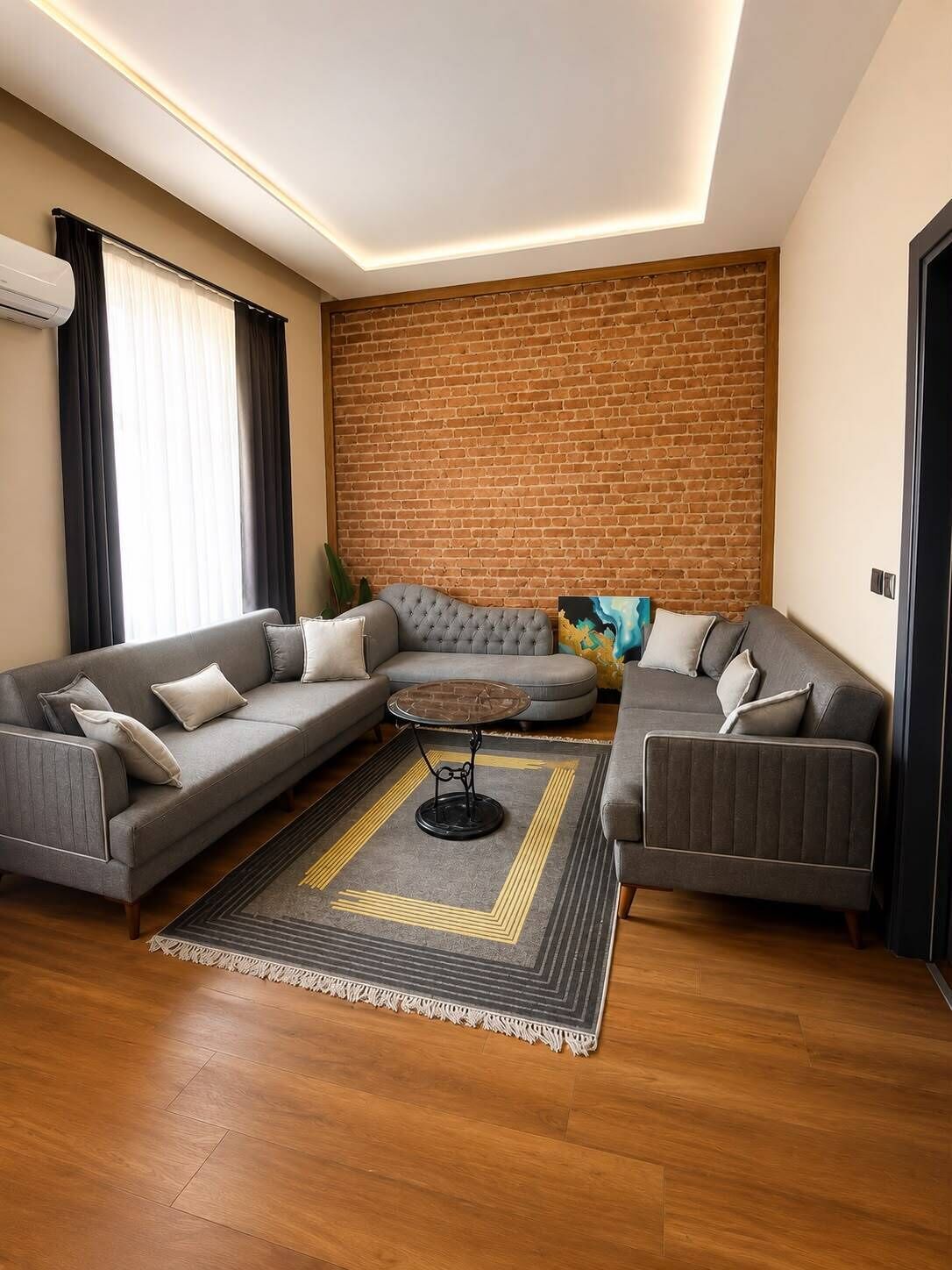 Uma sala de estar moderna com um sofá seccional, uma mesa de centro redonda e uma parede de tijolos como destaque.