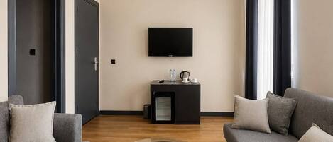 Uma sala de estar moderna com dois sofás, uma mesa de centro, uma TV de tela plana e um pequeno armário.