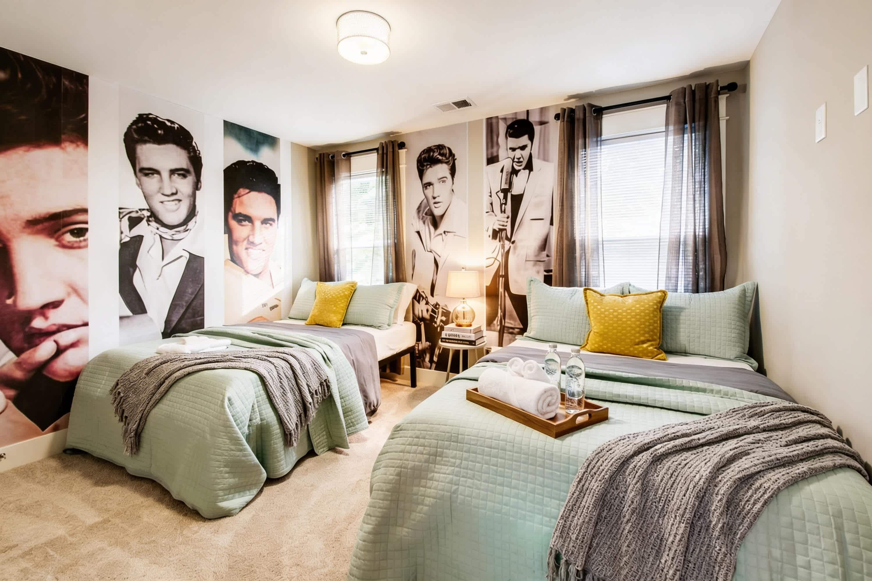 A hotel room with two beds, a large poster on the wall, and a window with curtains.