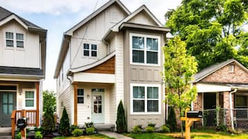 A residential building with a front porch, a mailbox, and a well-maintained lawn.