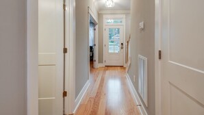 A hallway with wooden flooring, white walls, and a door at the end leading to a room. - Booking Fast 12 Beds-large Yard (Nashville)