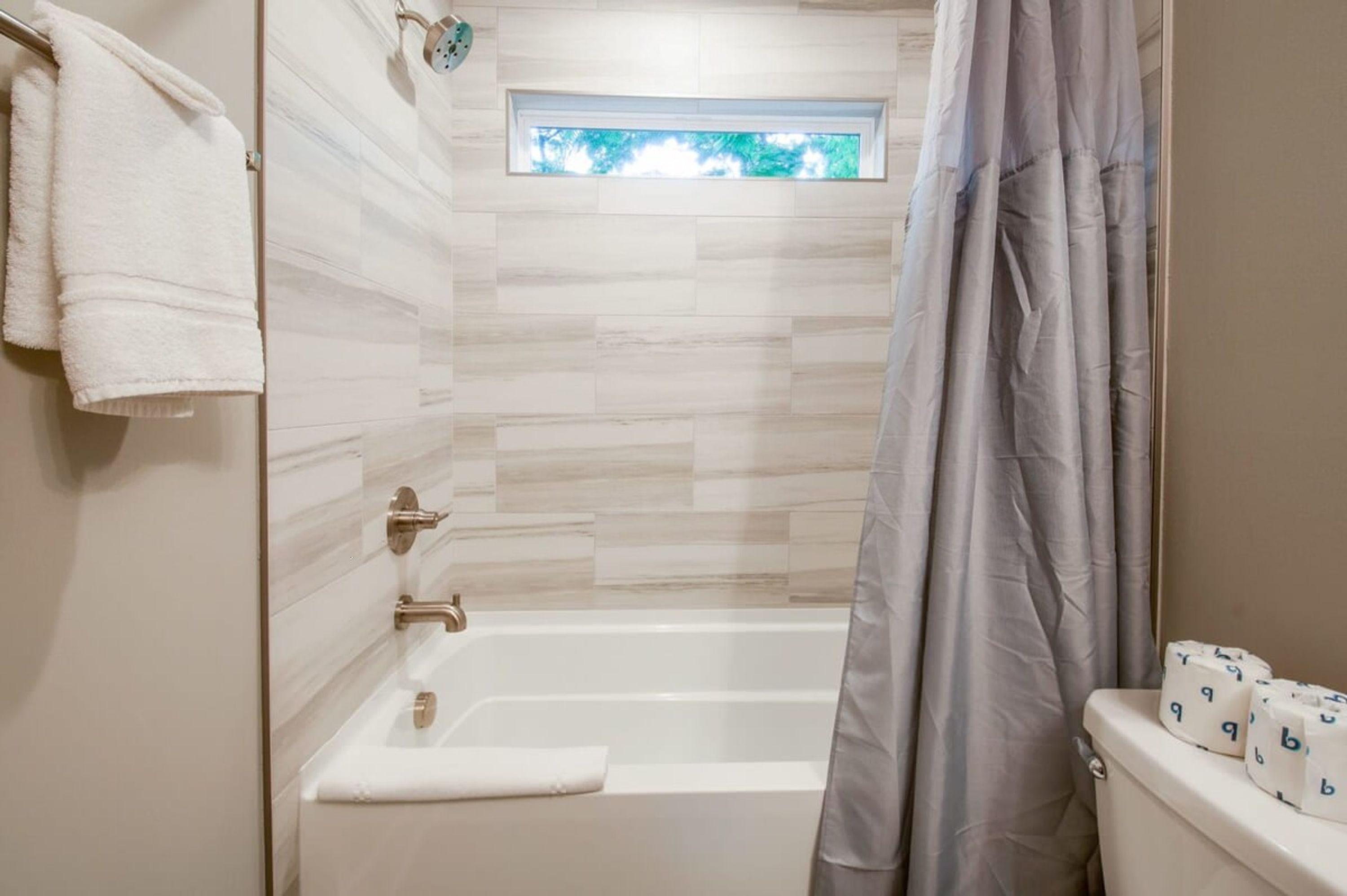 A bathroom with a bathtub, a window, and a toilet.