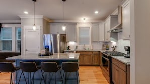 A modern kitchen with a central island, bar stools, stainless steel appliances, and wooden cabinets. - Booking Fast 12 Beds-large Yard (Nashville)