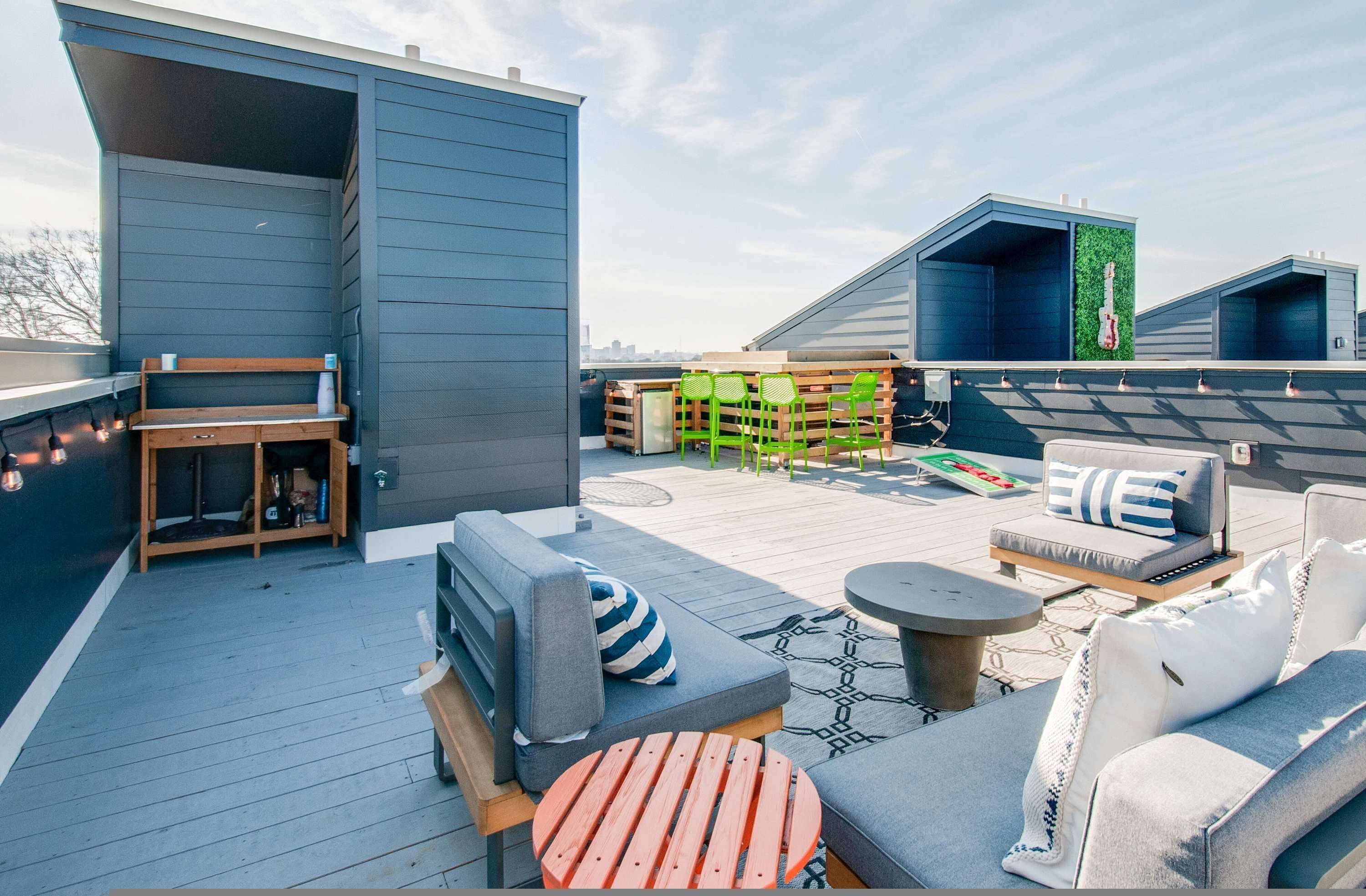 A rooftop patio with outdoor seating, a grill, and a guitar decoration.