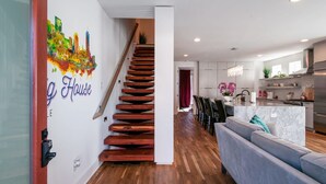 A modern kitchen with a marble island, wooden staircase, and a living area with a sofa.