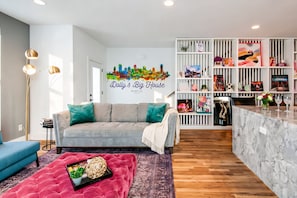 Una sala de estar moderna con un sofá gris, un pouf rojo y un mostrador de recepción de mármol.