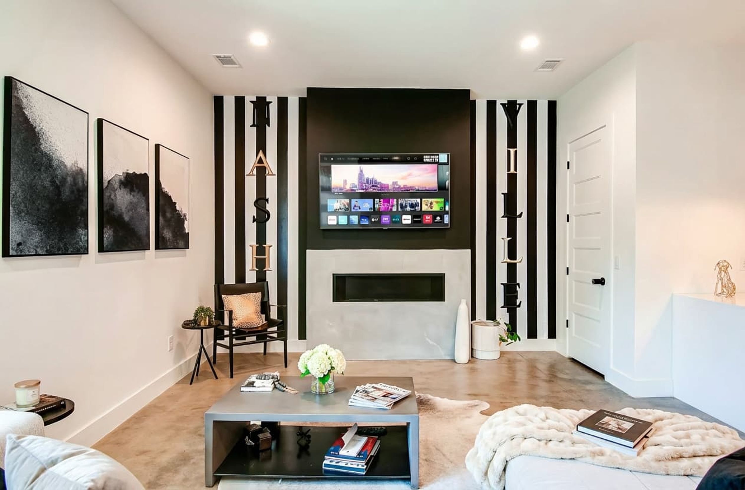 A modern living room with a flat-screen TV mounted above a fireplace, a sofa, a coffee table, and a chair.