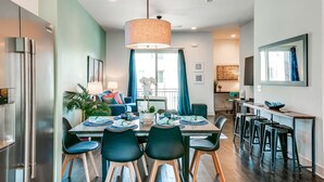 A modern kitchen with a dining area, featuring a large table, chairs, and a hanging light fixture. - Game Room and Skydeck - Book Today (Nashville)