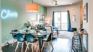 A modern living room with a dining area, a ceiling fan, and a neon sign. - Game Room and Skydeck - Book Today (Nashville)
