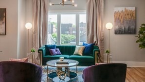 A modern living room with a green sofa, two armchairs, a coffee table, and a large window with curtains. - Large Group Lux 3mi Downtown - Rooftop City Views (Nashville)