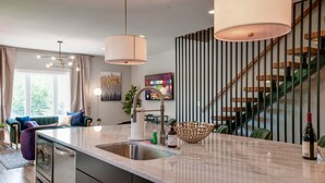A modern kitchen with a large island, stainless steel appliances, and a hanging light fixture. - Large Group Lux 3mi Downtown - Rooftop City Views (Nashville)