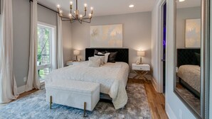 A bedroom with a large bed, bedside tables, a chandelier, and artwork on the wall. - Large Group Lux 3mi Downtown - Rooftop City Views (Nashville)