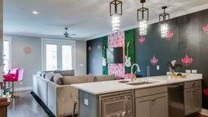 A modern kitchen with a central island, stainless steel appliances, and decorative wall art. - Close to the Gulch - Book Today (Nashville)