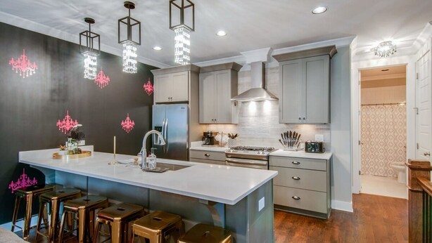 A modern kitchen with a central island, bar stools, stainless steel appliances, and pendant lighting. - Close to the Gulch - Book Today (Nashville)