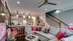 A modern living room with a sectional sofa, a round coffee table, and a kitchen in the background. - Close to the Gulch - Book Today (Nashville)