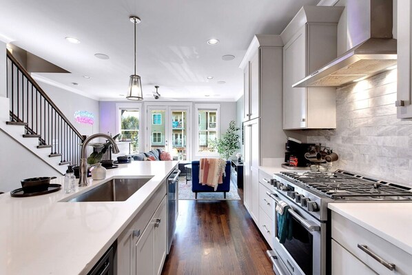 A modern kitchen with a central island, stainless steel appliances, and a view to a balcony. - Near Gulch 12 South Book Luxury Now (Nashville)