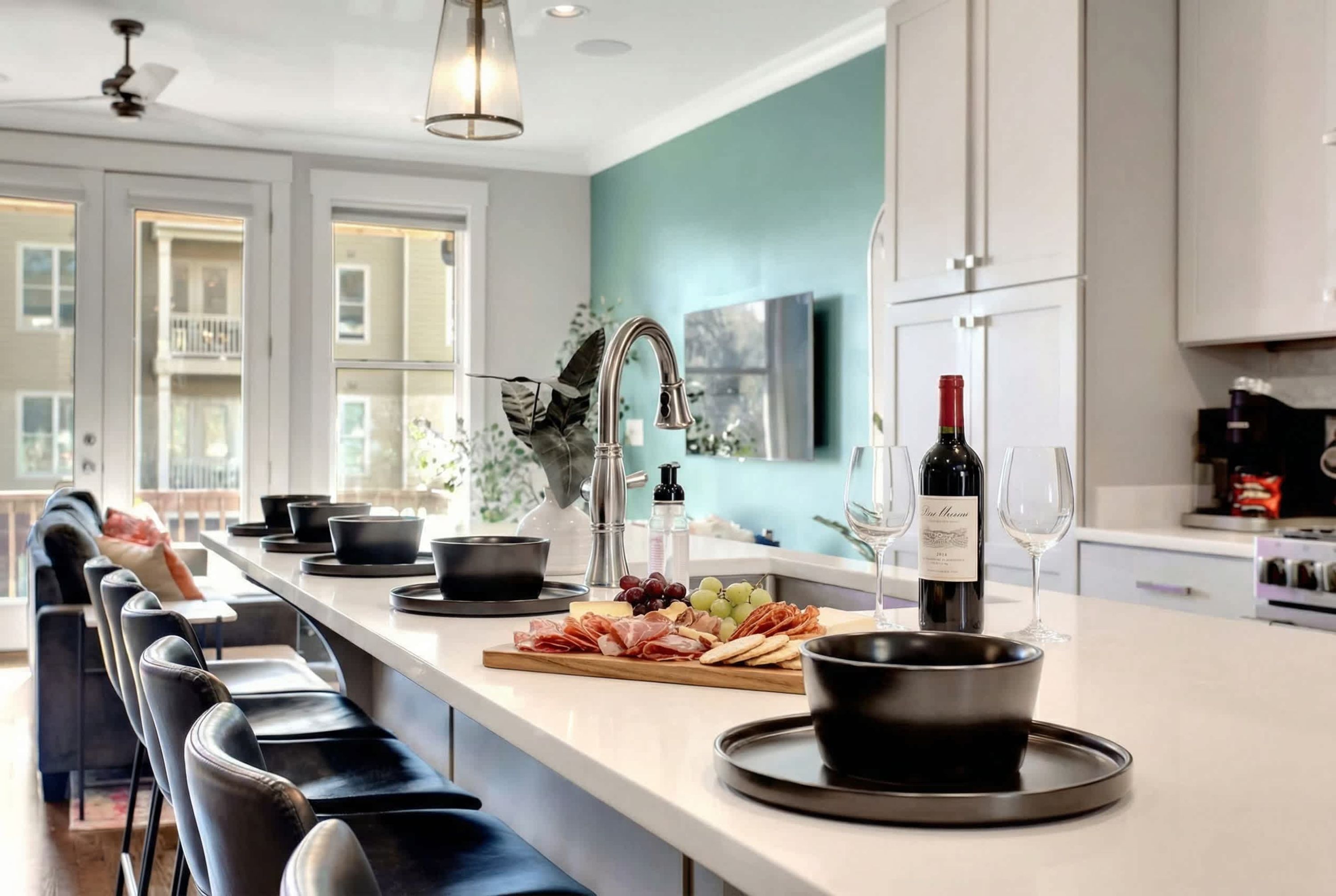 Een moderne keuken met een groot eiland, een bar en een wijnfles op het aanrecht.