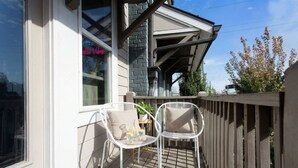 Een houten terras met twee witte stoelen en een kleine tafel met een plant.
