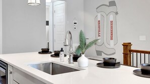 Een moderne keuken met een wit aanrecht, een roestvrijstalen spoelbak en een potplant.