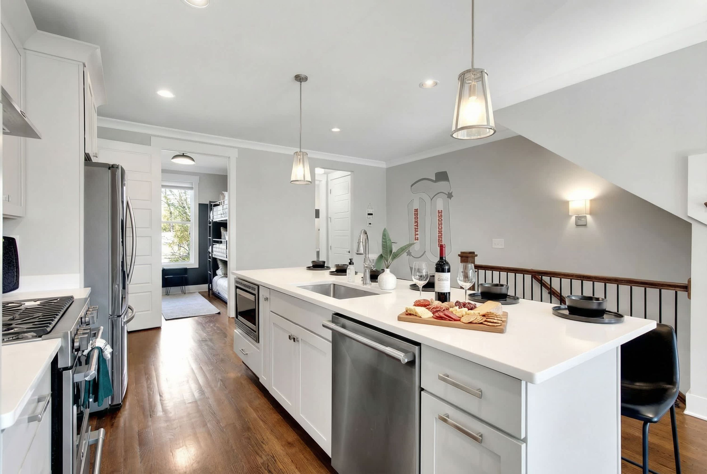A modern kitchen with white cabinetry, stainless steel appliances, and pendant lighting.