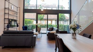 A modern living room with a sofa, a dining table, and a bookshelf. - THE CITY ZUG APARTMENTS (Zug)