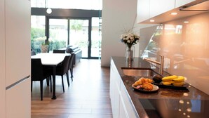A modern kitchen with a breakfast bar, a dining area with chairs, and a vase with flowers on the counter. - THE CITY ZUG APARTMENTS (Zug)
