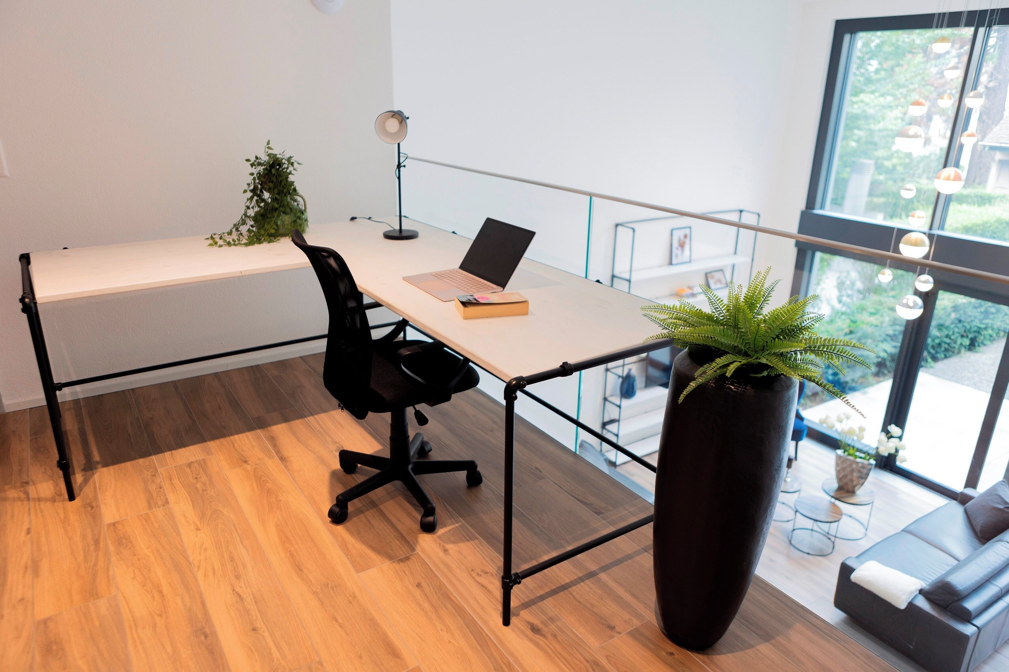 A modern office space with a desk, chair, laptop, and potted plant.
