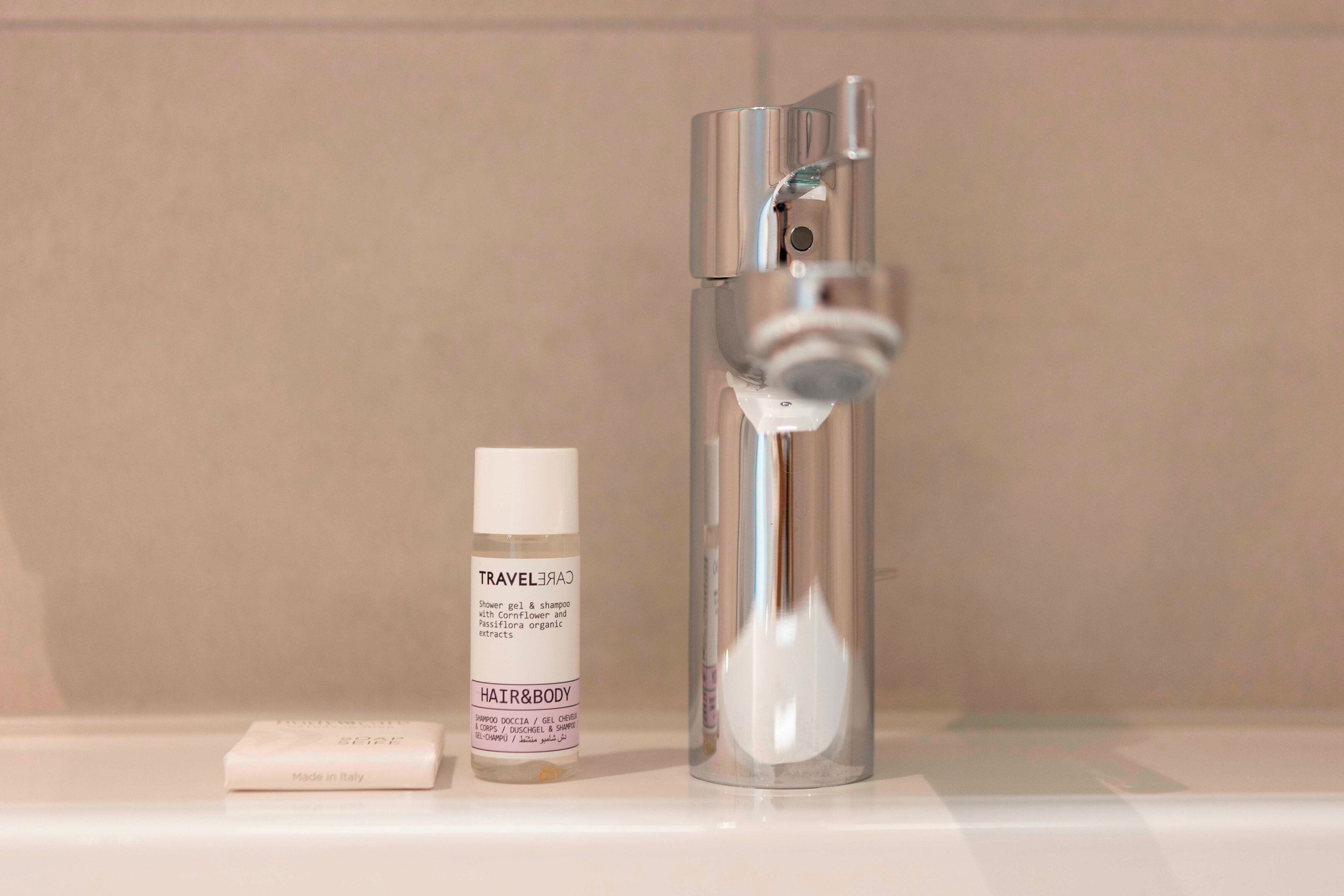 Un baño con ducha, una botella de producto capilar y para el cuerpo, y una pastilla de jabón.