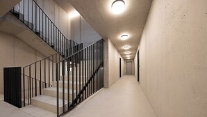 A modern interior with a concrete staircase, metal railings, and recessed lighting. - THE CITY ZUG APARTMENTS (Zug)