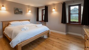 Ein Schlafzimmer mit einem hölzernen Bett, einem Gemälde an der Wand und einem Fenster mit Vorhängen.