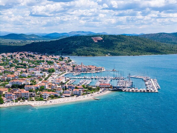 A coastal town with a marina, buildings with red roofs, and a beach.
