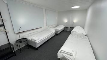 A hotel room with two single beds, a small table, and a chair.
