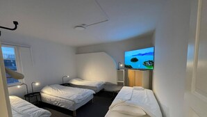 A hotel room with two single beds, a sofa, a TV on the wall, and a window. - Office Motel (Gothenburg)