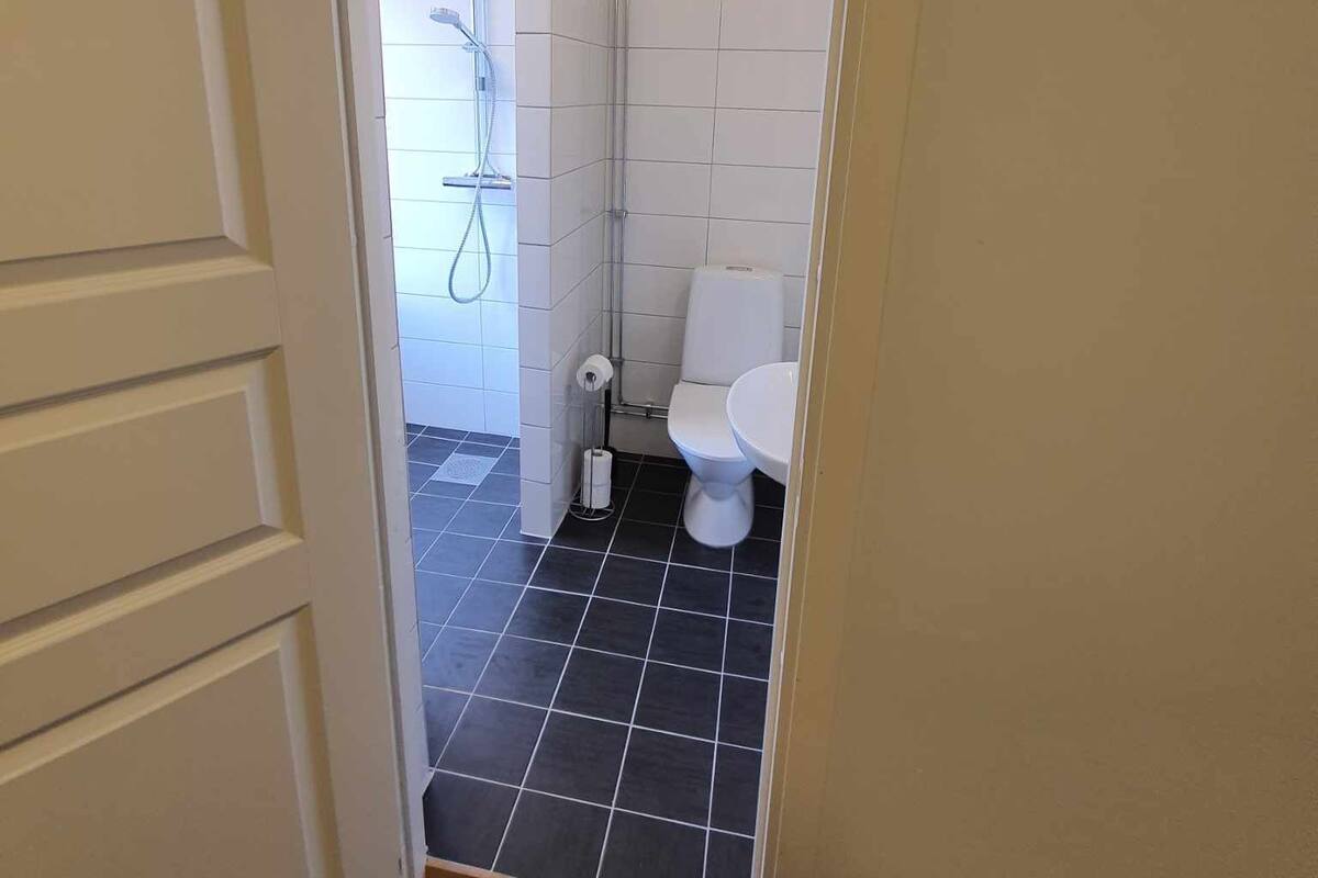 Ein Badezimmer mit Toilette, Duschbereich und Fliesenboden.