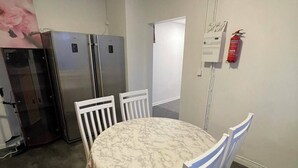 A conference room with a marble table, white chairs, a whiteboard, a fire extinguisher, and two refrigerators. - Office Motel (Gothenburg)