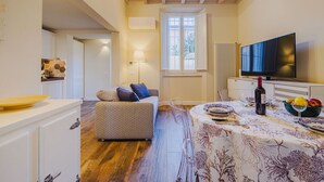 A cozy living room with a wooden ceiling, a sofa, a dining table set for two, and a television. - Beautiful  villa for 5 people with WIFI, A/C, TV and patio (Camaiore)