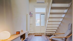 A room with a wooden floor, a white wall, a wooden chair, a small table with a lamp, and a staircase. - Beautiful  villa for 5 people with WIFI, A/C, TV and patio (Camaiore)